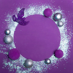 Christmas background with copy space. Purple background with free space in the form of a circle, decorated with artificial shiny snow and Christmas toys of purple and silver color.
