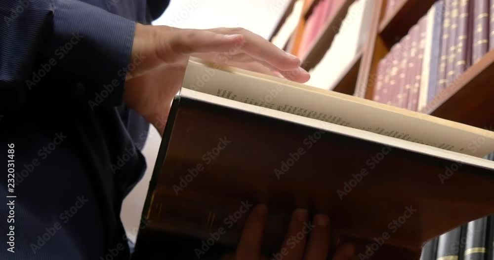 Poster close-up low angle view of a person leafing through the pages of a book in a library or book store