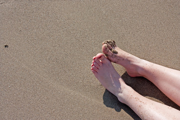 Woman's legs and feet on a wet sandy beach