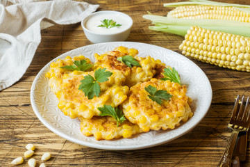 Cutlets from grains of canned corn with parsley on a plate. Wooden background.