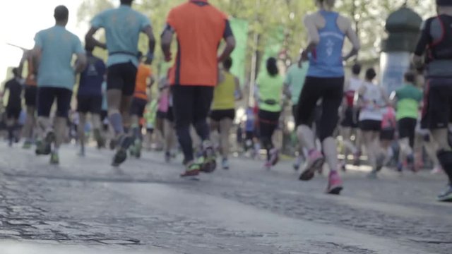 Slightly out of focus marathon runners, running on parisian pavement