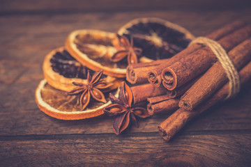 Spices for mulled wine: cinnamon sticks, star anise, slices of orange on a wooden background.