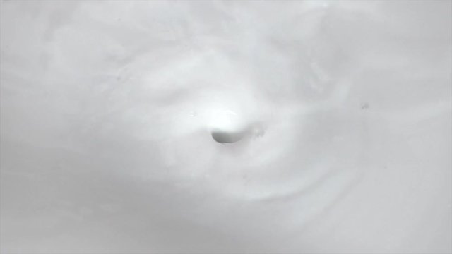 Footage of creamy milk swirling whirlpool and pouring with bubbles background for food dairy product
