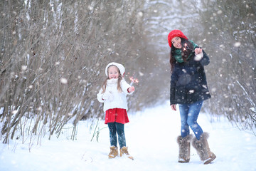 A winter fairy tale, a young mother and her daughter ride a sled in the forest. A girl on a sled with gifts on the eve of the new year in the park. 