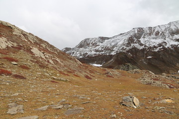 Mountains in autumn with brown and reddish grass under cloudy sky