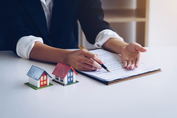 Estate agent use the pen pointing on document showing where to sign. Signing a paper document for buying house.Real estate, home loan and insurance concept