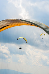 Paraglider is flying in the blue sky against the background of clouds. Paragliding in the sky on a sunny day.