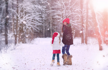 A winter fairy tale, a young mother and her daughter ride a sled in the forest. A girl on a sled with gifts on the eve of the new year in the park. 