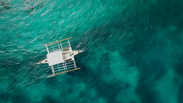 Aerial view of single filipino fishing boat sailing in turquoise water near Lapu-Lapu city, Philippines.