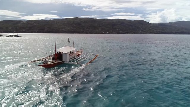 Aerial view following single filipino fishing boat sailing near Lapu-Lapu city, Philippines.