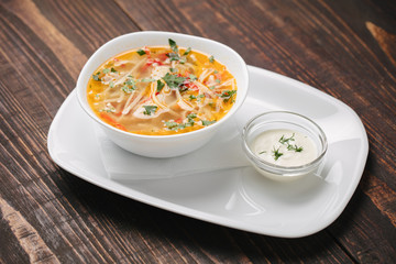 Chicken soup on a white plate served with sour cream