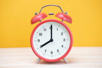 vintage retro alarm clock eight minutes to twelve time o'clock on table wood with yellow background. 