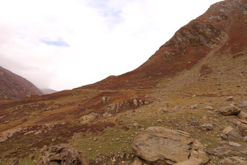 Mountains in autumn with brown and reddish grass under cloudy sky