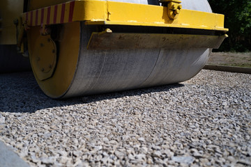 road roller performing road works on leveling of fresh asphalt