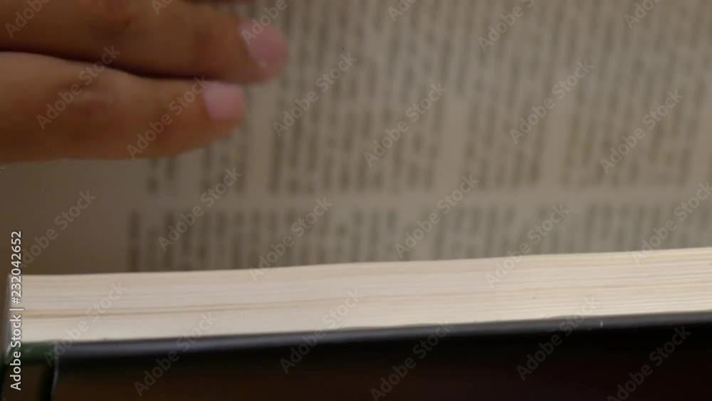 Poster close-up side view of a person turning the pages of a book