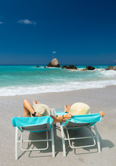 Couple on sunbeds relaxing at the beach in Lefkada