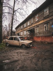 Abandoned place, mud all around, old car stuck in the mud, wooden house almost collapsed
