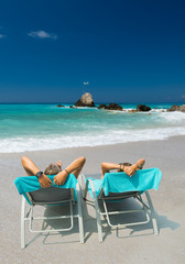 Fototapeta na wymiar Couple on sunbeds relaxing at the beach in Lefkada