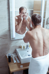 Handsome man with nice muscle body shaving his face after taking shower