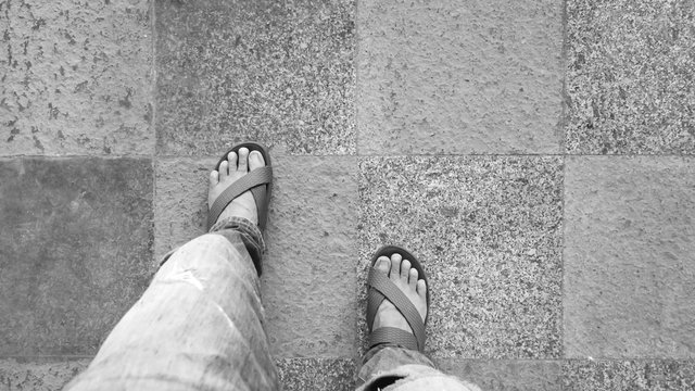 Man wearing blue slippers on the floor walkway paved with slabs, Black and white concept.