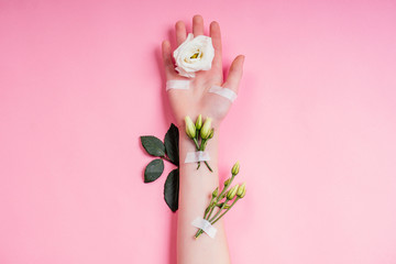 Nude manicure.Natural freshness and youth girl hands ,hand cosmetics with white rose flower adhesive plaster .Fashion woman hand with flowers and leaves,herbal skin care pink background studio shot