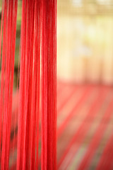 Close up red thread from weaving machine traditional craft in Thailand