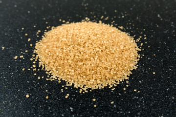 Scoop of raw cane sugar isolated over black