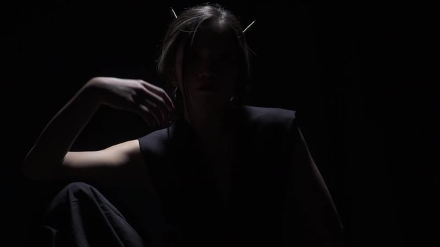Japanese woman posing in the dark, black background, slight slow motion