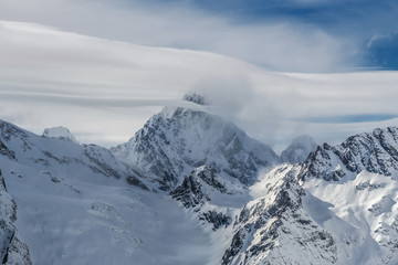 Obraz premium Snow covered Mt. Aksaut in clouds. Dombay ski resort, Western Caucasus, Russia.