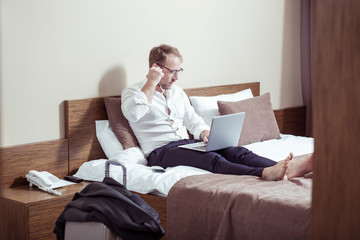 Fototapeta premium Blonde-haired businessman using earphones for video chat in hotel room