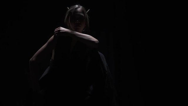 Asian woman bares her shoulders in the dark