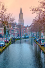 Evening view of the canal and the church in Delft near Amsterdam. Dutch city in the spring after sunset. Holland, Netherlands.