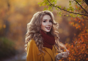 Beautiful autumn portrait of a young smiling mother. Young happy woman in autumn clothes walking in the Park.
