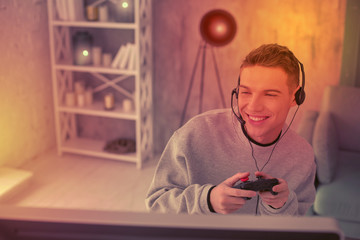 Enthusiastic young fellow using gamepad for videogame