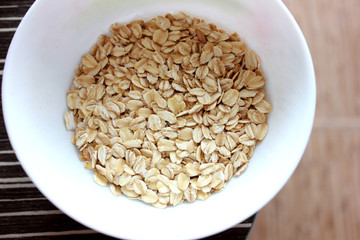 Oat flakes in a white bowl on brown