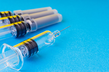 Medical syringe on blue background with selective focus and crop fragment