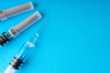 Medical syringe on blue background with selective focus and crop fragment