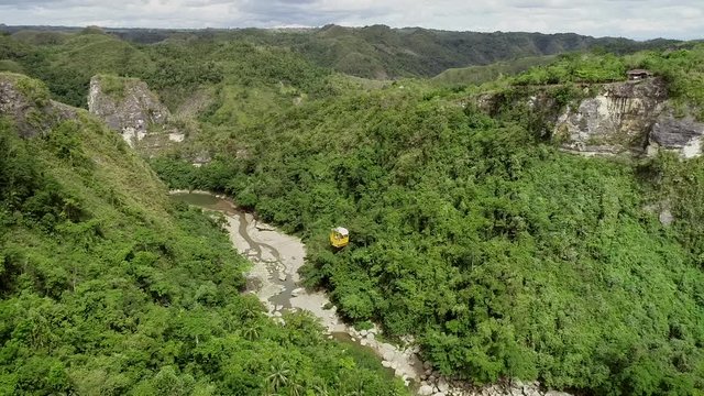 Aerial view of cable car with girl waving above Inabanga river in Danao, Philippines.