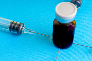 Medical syringe and vial on blue background with selective focus and crop fragment