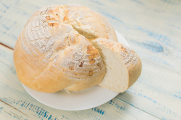 Round white bread on a wooden background.