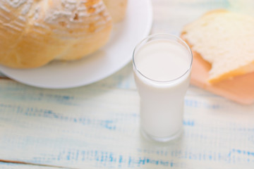 A glass of milk and white bread on a wooden background.