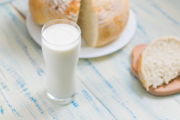 A glass of milk and white bread on a wooden background.