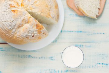 A glass of milk and white bread on a wooden background.