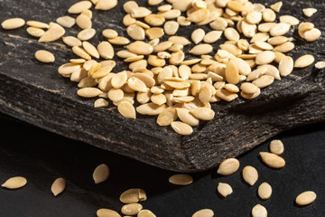 Pile of shelled melon seeds on a slab of black rock.