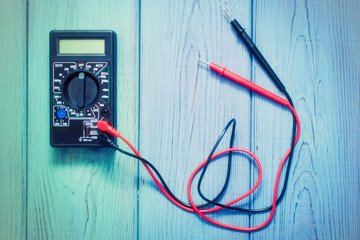 Electronic multimeter to measure the current on a wooden background.