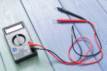 Electronic multimeter to measure the current on a wooden background.
