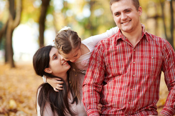 Happy family is in autumn city park. Children and parents. They posing, smiling, playing and having fun. Bright yellow trees.