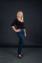 Mature woman 60 years old in full growth against a dark background.