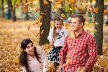 Happy family is in autumn city park. Children and parents. They posing, smiling, playing and having fun. Bright yellow trees.