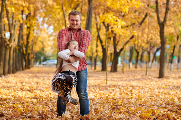 Father and daughter are playing and having fun in autumn city park. They posing, smiling, playing. Bright yellow trees.